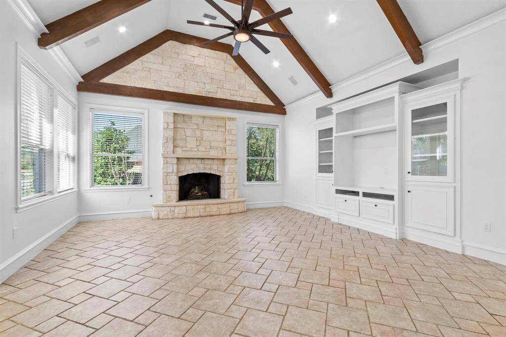 Expansive family room with a striking wood-beamed ceiling that adds character and warmth to the space.The raised Limestone fireplace serves as a focal point, while the built-in entertainment center is perfect for all your TV and stereo needs!