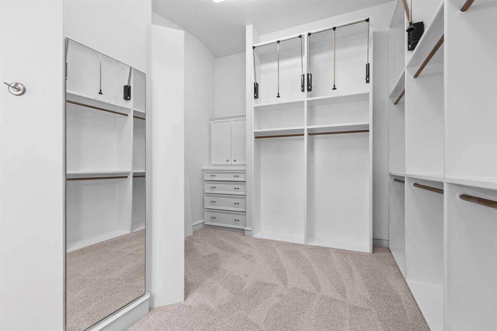 Huge walk in closet decked out with multiple shelving, drawers and mirror.