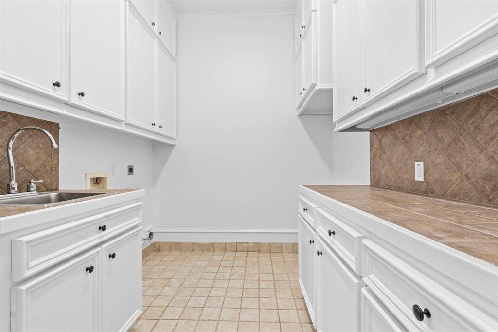 The utility room is exceptionally spacious, offering a deep sink, ample storage, and plenty of countertop space. This home is equipped with an overabundance of storage throughout.