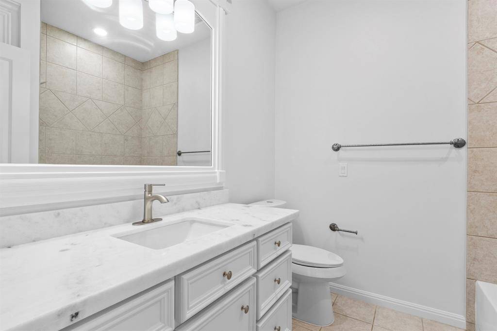 Bathroom #5 boasts Quartz countertops, a new toilet, updated faucet, reglazed tub, and a built-in framed mirror.