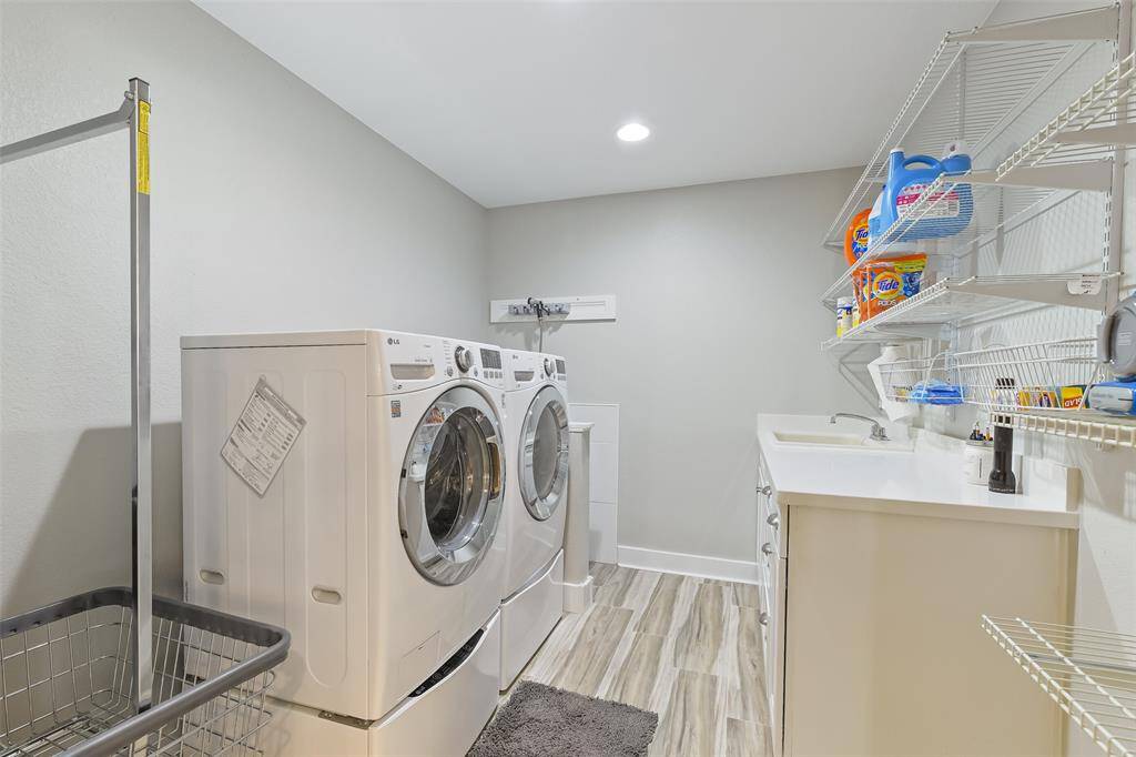 This modern laundry room features a stylish sliding barn door, ample storage, a convenient sink, and a dedicated pet shower stall.