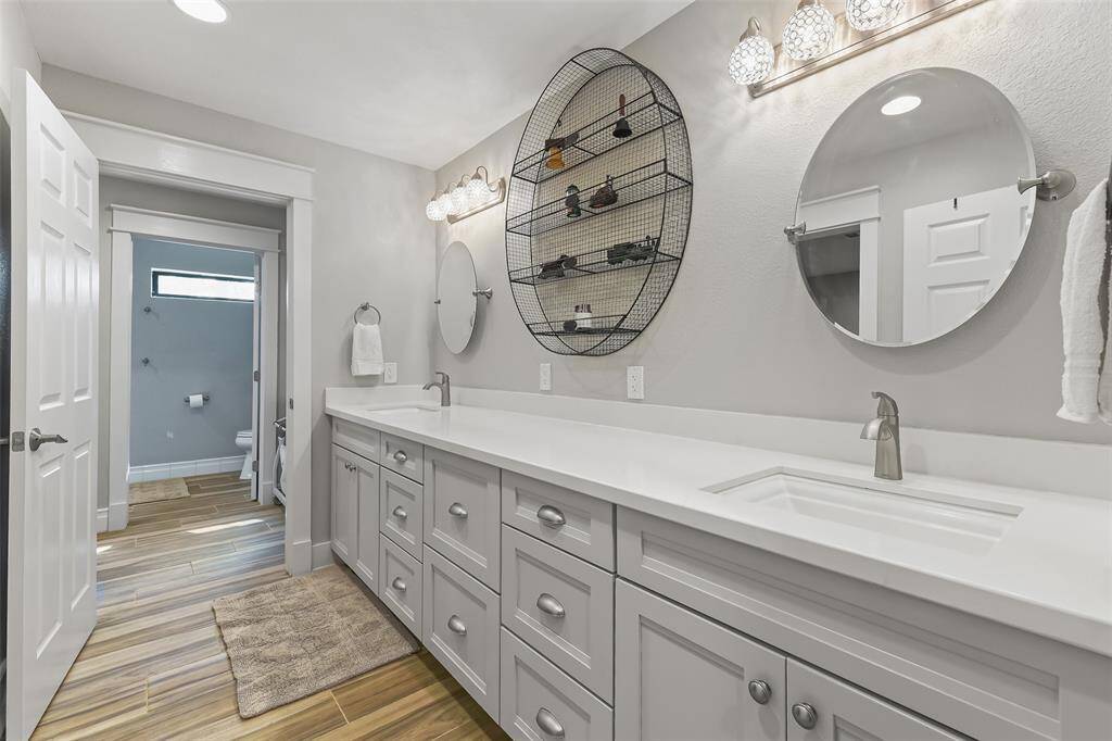 Spacious primary bathroom featuring double sinks, quartz countertops, ample storage with 24 inch deep cabinets and eight soft-close drawers, complemented by elegant mirrors.