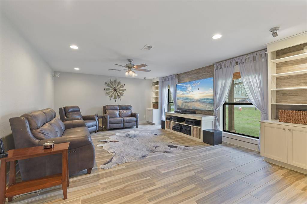 Expansive family room with recess lighting, a ceiling fan, wired for surround sound, and built-ins with a stylish plank wood wall.