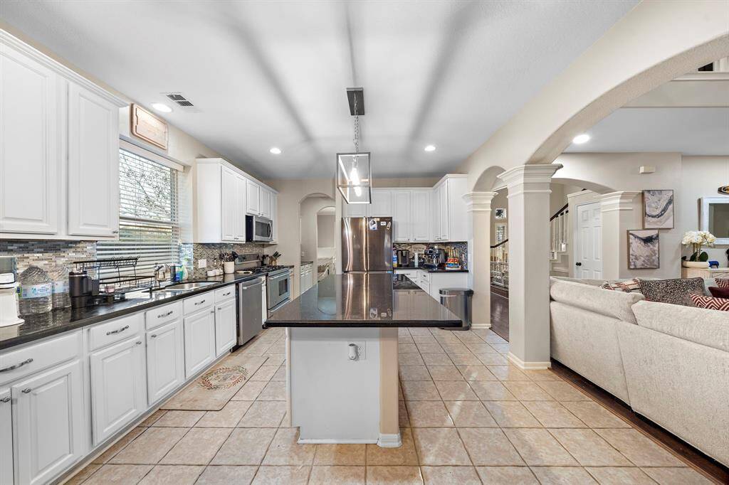This beautifully updated kitchen features a sleek, oversized island with ample counter space, perfect for meal prep and casual dining. The open layout flows seamlessly into the living and dining areas, enhancing the home's spacious and inviting feel.