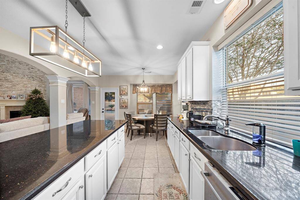 Natural light pours into the kitchen and breakfast nook through large windows, highlighting the modern finishes, updated backsplash, and stainless-steel appliances. The open floor plan ensures effortless entertaining and connectivity.