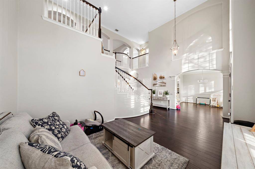 A versatile space with large windows and a modern light fixture, perfect for use as a playroom or home office. Plantation shutters provide privacy and style.