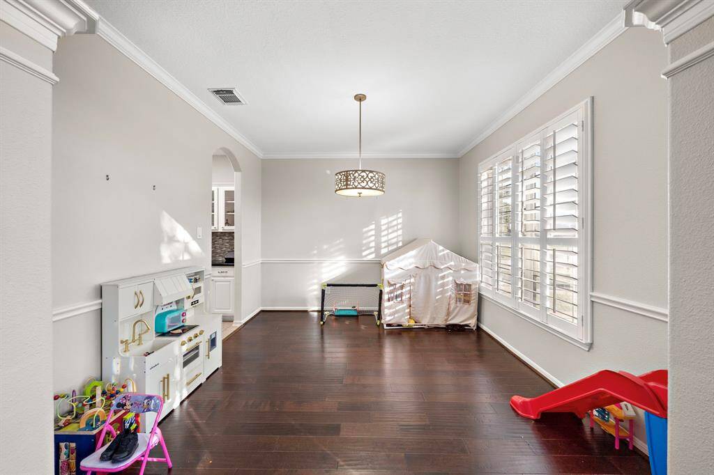 A versatile flex space illuminated by a chic light fixture and large windows. This room is perfect for playtime, hobbies, or a creative workspace