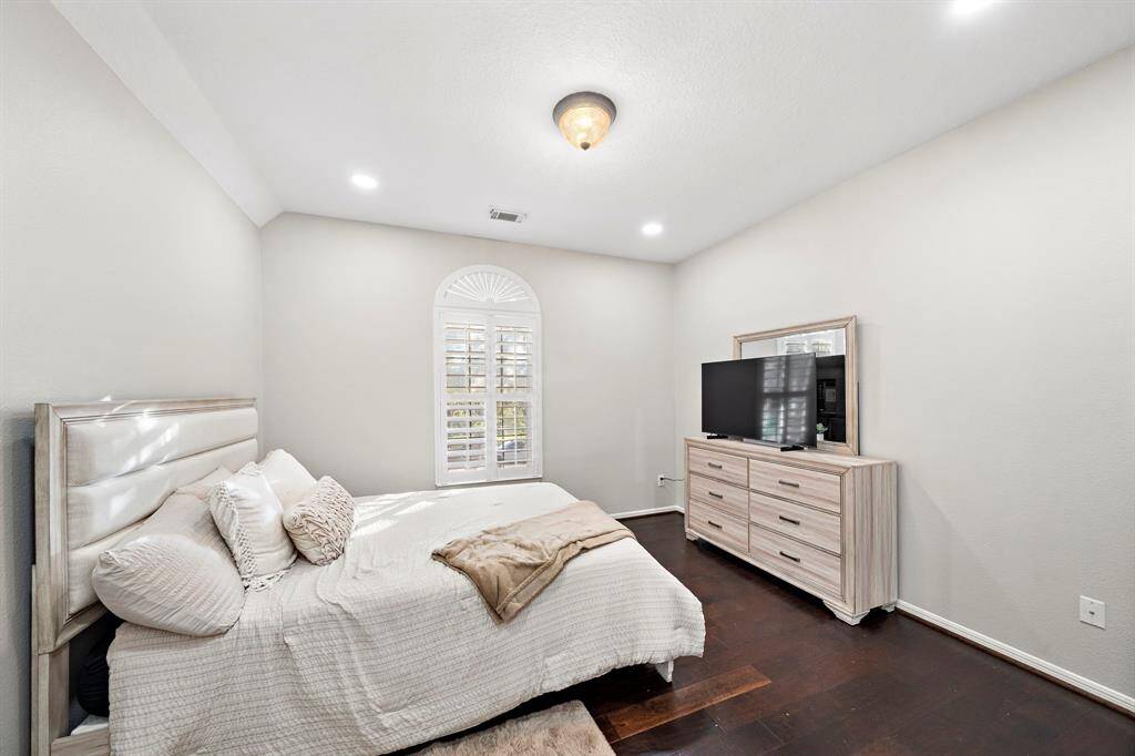 A serene bedroom with a classic arched window and ample natural light. Its cozy ambiance makes it an ideal retreat for rest and relaxation