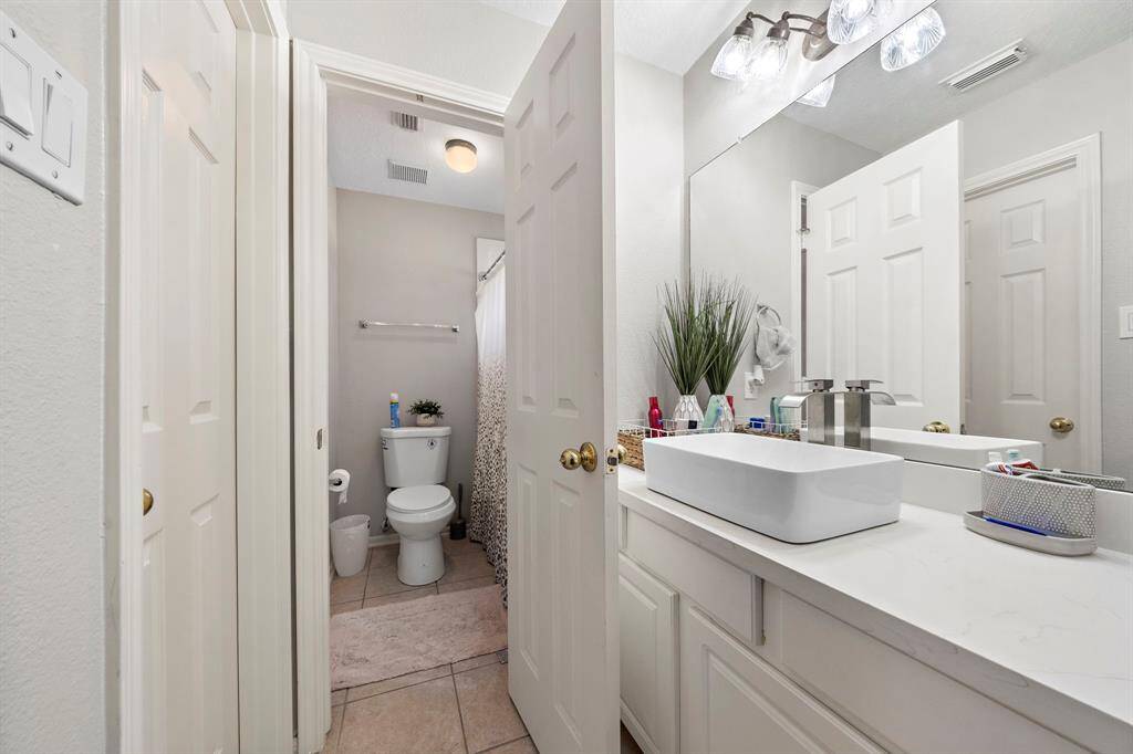 This well-lit bathroom features a charming vanity area and a bright shower space. Elegant accents and practical design make it perfect for guests.