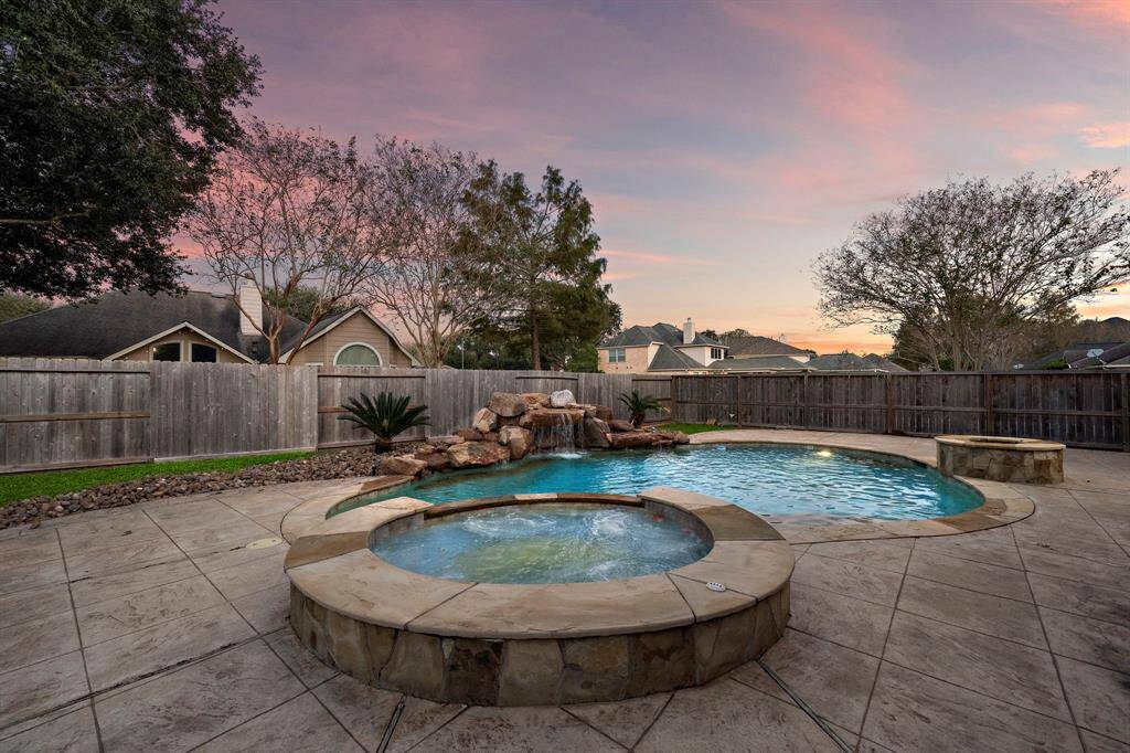 Bask in the beauty of this backyard retreat, featuring a resort-style pool and spa surrounded by lush landscaping and elegant stone accents.
