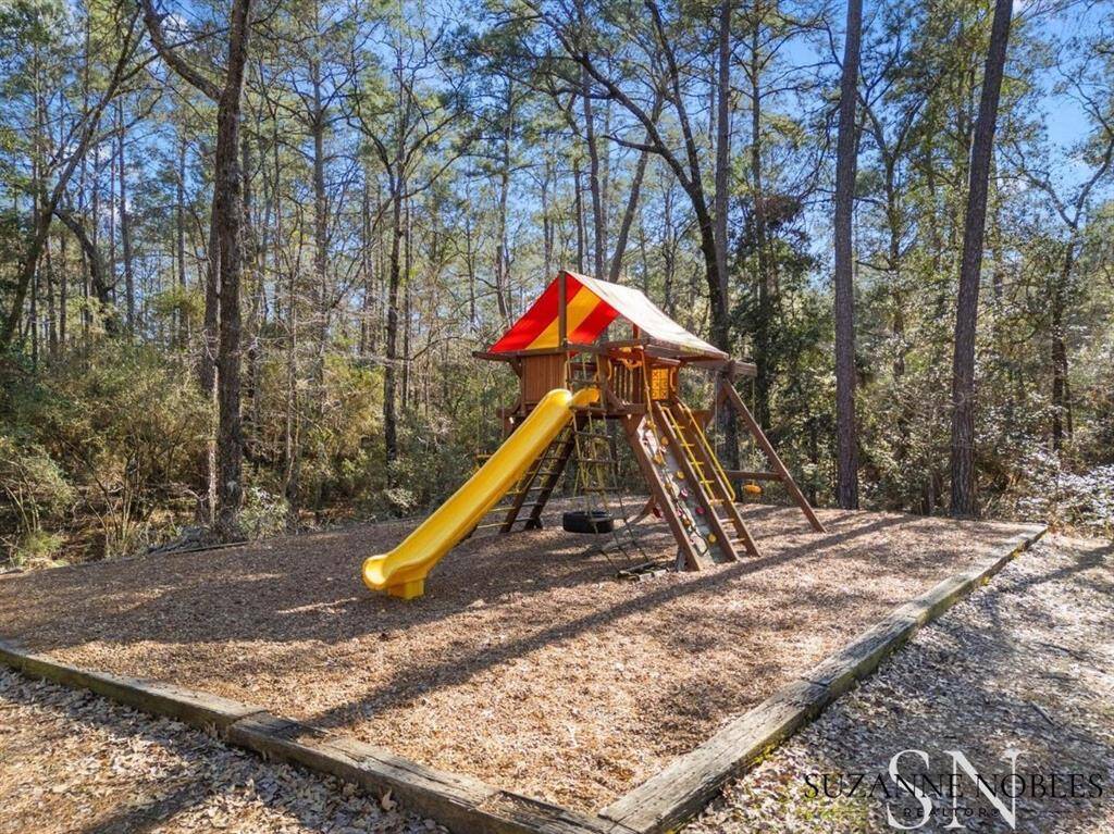 The playground includes a slide, tire swing, swings, and a fun rock-climbing wall.