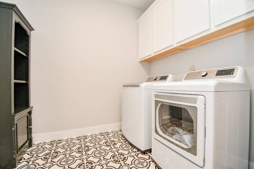 The laundry room features cabinetry for storage, and stylish patterned flooring, creating a functional and attractive space.