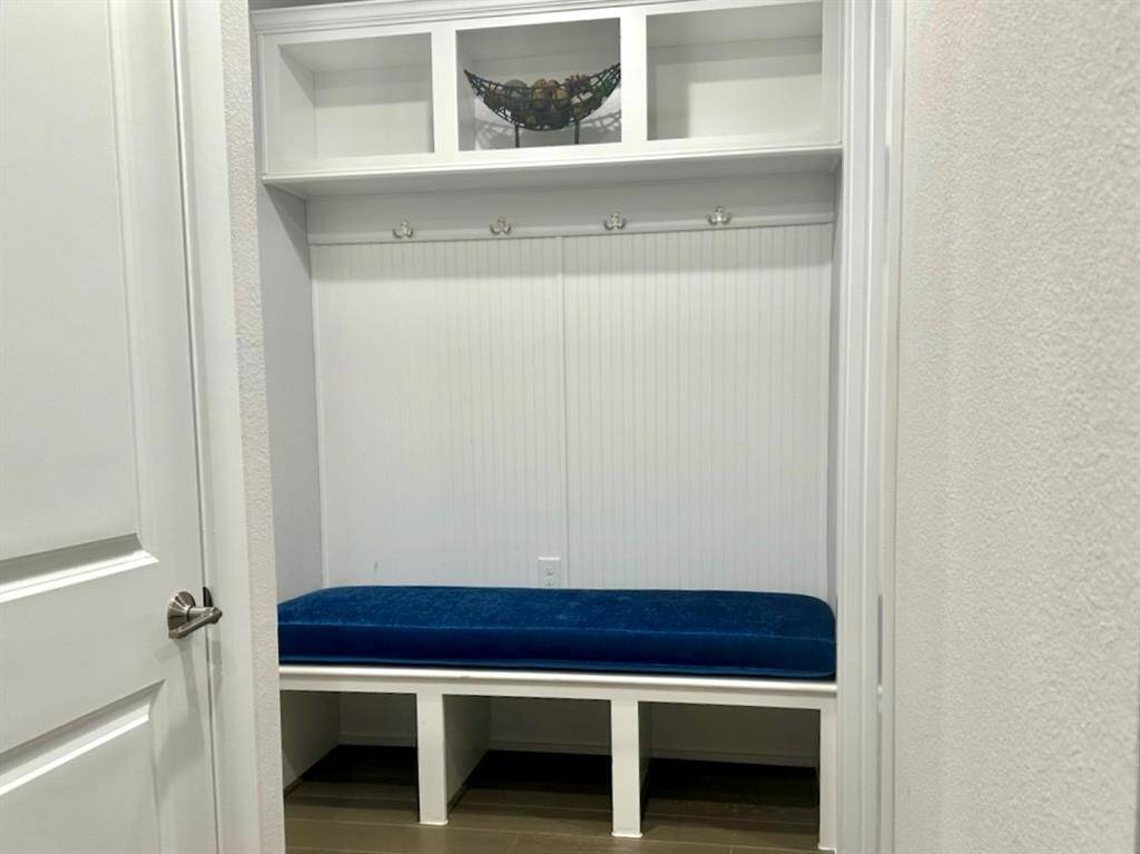 The mud room is located between the garage and the laundry room. It is complete with, hanging hooks and shelving both above and below the bench.