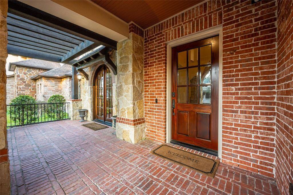 The inviting covered front porch and front pergola create a charming entryway, complemented by coach lighting and elegant iron railing. This beautifully designed space enhances curb appeal while offering a welcoming spot to relax and enjoy the surroundings. The stunning stone and brick exterior is beautifully accented by elegant French doors that open into the dining room, adding timeless charm and sophistication to the home's design.