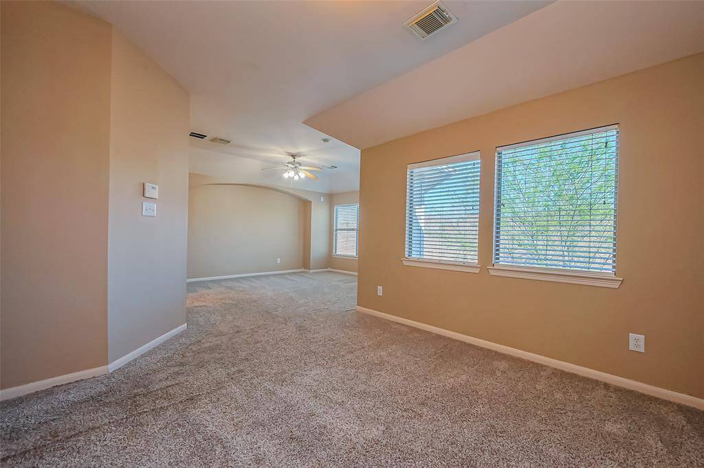 This spacious primary room features plush carpeting, soft neutral walls, and large windows that welcome an abundance of natural light. A ceiling fan adds year-round comfort, while the additional cozy alcove offers the perfect spot for a reading nook, home office, or private retreat. A serene and flexible space designed for relaxation and personalization.
