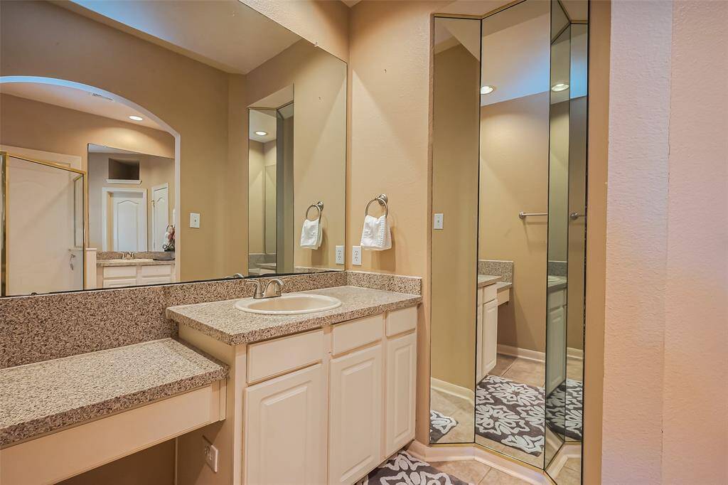 This bathroom features a granite countertop with an integrated sink, ample cabinet storage, and a large mirror. The space is well-lit and has a neutral color scheme, creating a warm and inviting atmosphere.