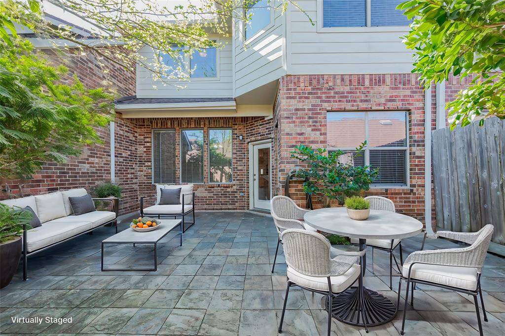 This photo showcases a charming outdoor patio area.  The space is enhanced by greenery, creating a private and inviting atmosphere perfect for dining outside, relaxation or entertaining.