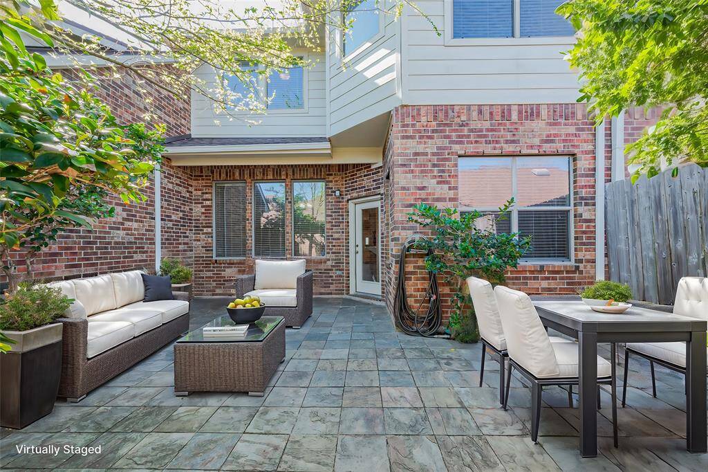 This photo showcases a spacious, private patio area with a tiled floor and brick exterior, surrounded by a wooden fence, perfect for outdoor relaxation or entertaining.