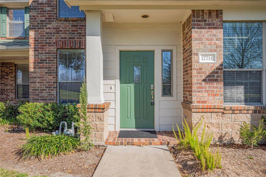 Welcome to your charming townhome, featuring a stylish green front door and inviting brick exterior.