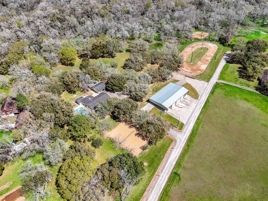 Welcome to this one-of-a-kind property. From this vantage point, you can see the main house, pool, and guest house/garage on the left, the volleyball court in front, the shop on the right, and beyond, the racetrack and pond. This exceptional property is unlike any other and definitely worth a visit!