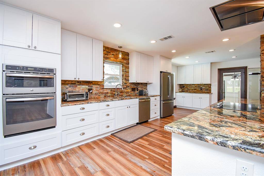 This kitchen is equipped with double ovens, with the top one doubling as a convection oven and microwave. Just take in all that cabinet space! The recessed lighting adds brightness, and the stunning fixture over the sink ties the space together beautifully.