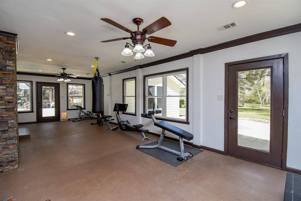 Here’s another view of this spacious sunroom, offering a view of the back of your property. It features two doors that lead outside—one towards the garage apartment and the other towards the pool area. Take note of the recessed lighting and dual ceiling fans, ensuring maximum comfort throughout the space.