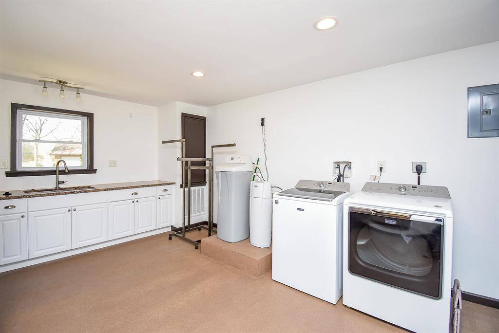 This utility room is incredible! It offers abundant space, along with a large walk-in closet featuring built-in shelving. You'll also find a sink with extra counter space and plenty of cabinet storage. Additionally, this home comes equipped with a water filtration system and water softener. The washer and dryer are negotiable.