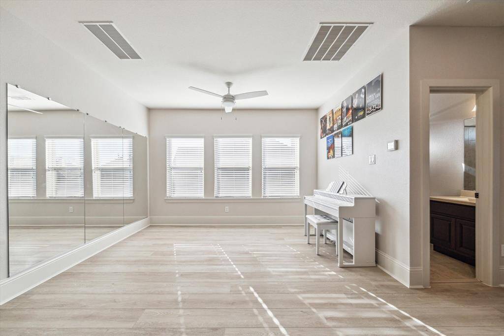 Bright and inviting upstairs game room with a ceiling fan and expansive windows for abundant natural light.
