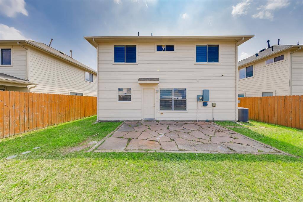 The backyard features a stone patio, perfect for relaxing or gathering with friends under the stars.