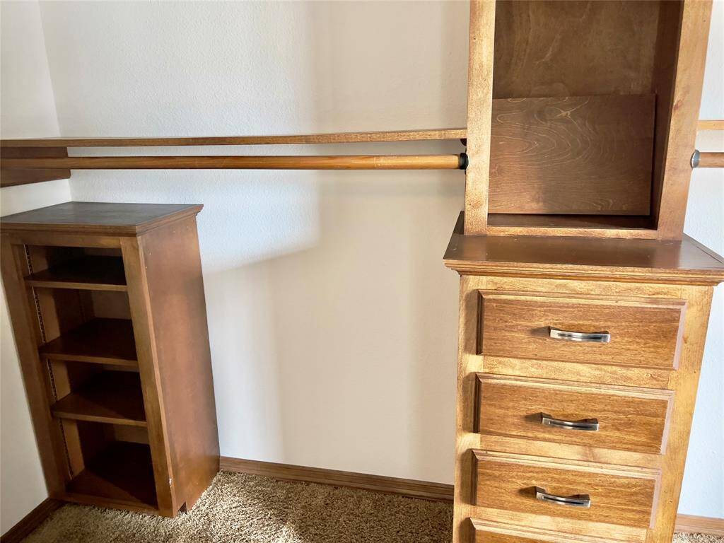 This photo shows a room corner with a built-in wooden closet organization system, including shelves and drawers, offering ample storage solutions for a tidy and efficient space.