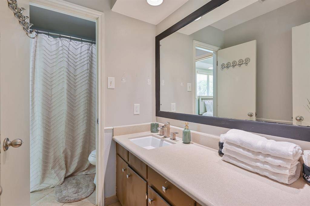 Thoughtfully designed, this full bathroom features an expansive vanity with a large, well-lit mirror. The vanity’s under-storage provides practicality, while a separate vanity area adds convenience. A clean and modern look enhances the appeal of the space.