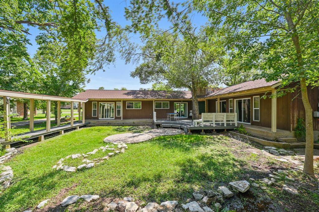 A lush, open green space framed by mature trees, creating a peaceful backdrop. The covered walkway adds a functional touch, providing shelter while maintaining a connection to nature. A perfect setting for outdoor activities and quiet moments alike.