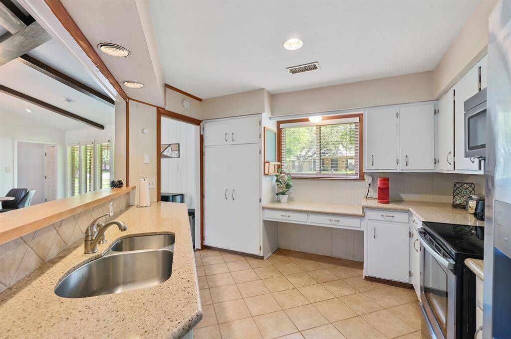 Designed for both style and efficiency, this spacious kitchen overlooks the dining and living areas through a raised bar, keeping the space open yet functional. Ample cabinetry above and below provides generous storage, while expansive countertops ensure plenty of room for meal prep. A double sink, sleek stainless steel appliances, and recessed lighting add modern convenience, making this a well-lit and practical culinary space.