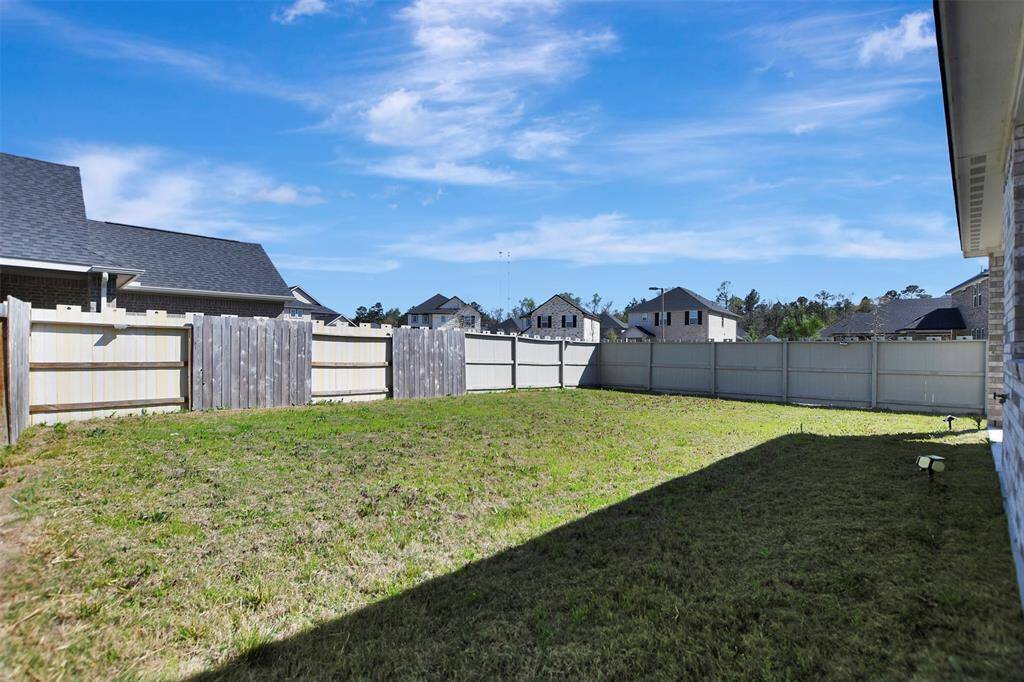 Spacious, fenced backyard with a mix of wood panel fencing, ideal for privacy. The area is grassy and well-maintained, perfect for outdoor activities.