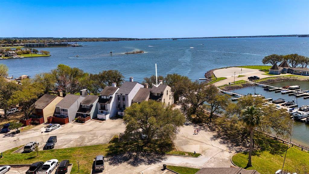 An aerial view of the home, which shows the lake and surrounding established shade trees and marina. The dues cover yard maintenance up to 3 ft. from the home, pest control & all amenities including the gate to the complex.