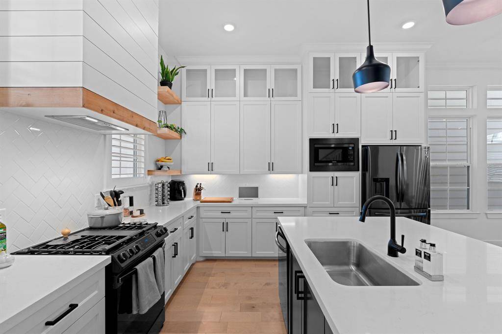 This sleek open concept kitchen offers black stainless-steel appliances, quartz countertops and soft-close cabinets adding a touch of luxury.