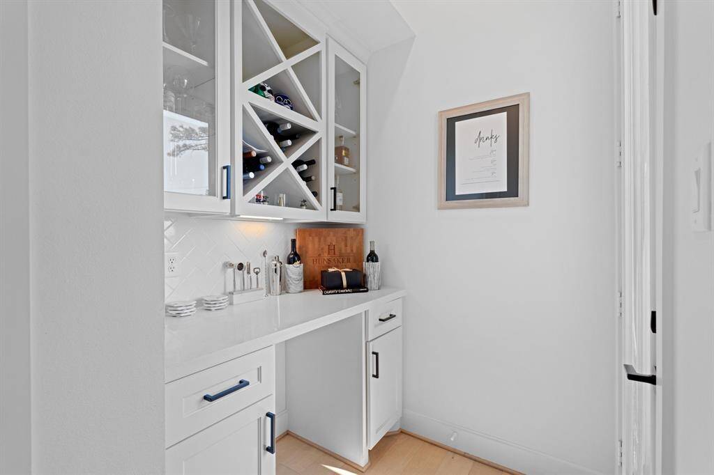 The bar area is conveniently located just off the kitchen, featuring cabinet storage and space for a wine fridge. This area could also be used as a work from home space. You'll find access to the second floor balcony directly across.
