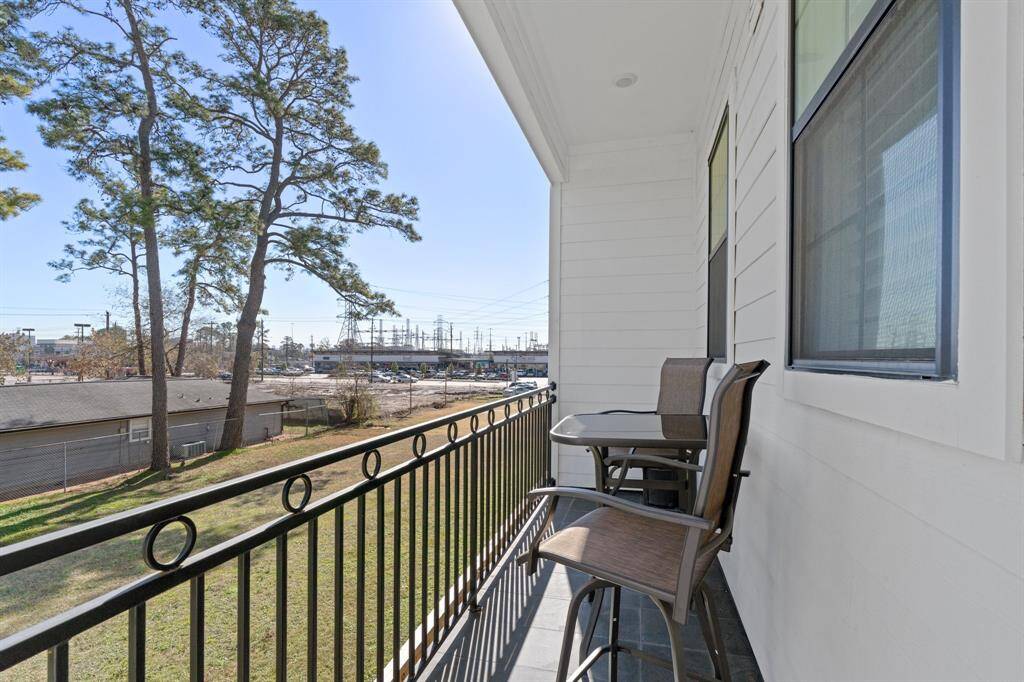 The second floor covered balcony offers private, serene views of the green space behind this home.