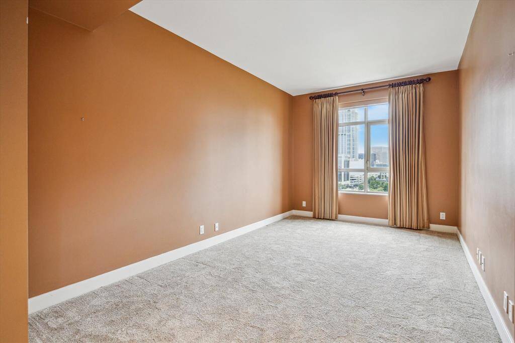 The warm-feeling secondary bedroom with drapery and large window.