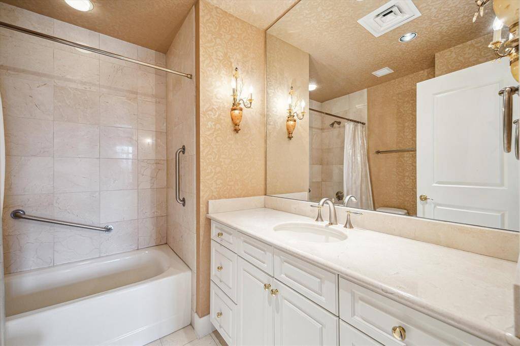 Secondary bathroom with a tub/shower, counter to ceiling mirror, marble countertop and under counter storage.