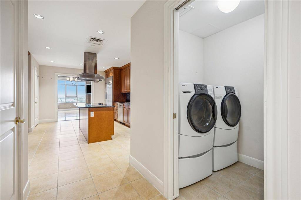 The utility room with a full size washer and dryer along with another view of the kitchen.