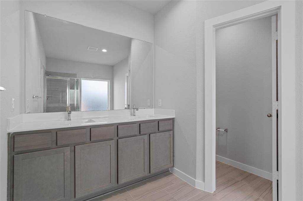 This large primary bath is spacious enough to share! With separate vanities, large closet space, plentiful cabinet and counter space, you are sure to have private area while sharing this bathroom!