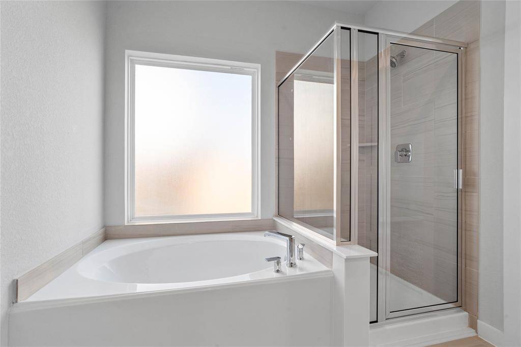 This primary bathroom is definitely move-in ready! Featuring a large garden tub to soak in after a long day, and a framed walk-in shower with tile surround!