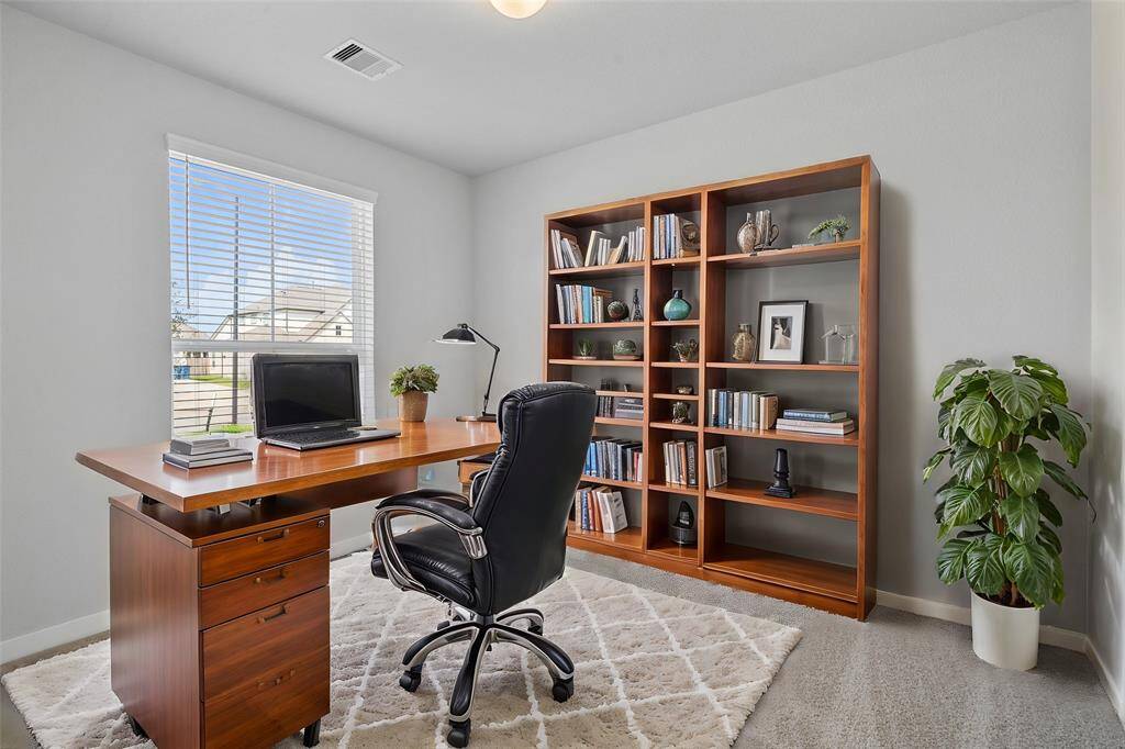 Quietly nestled in front of the home is the handsome home office. Featuring plush carpet, high ceilings, large windows with privacy blinds and custom paint.