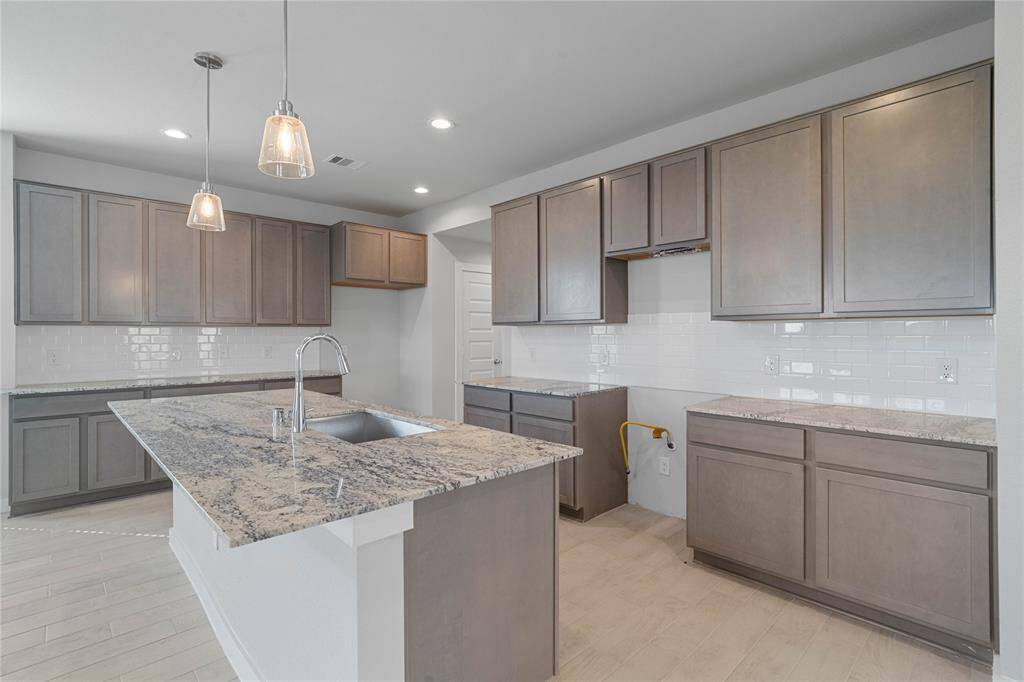 This kitchen is by far any chef’s dream! This spacious kitchen features high ceilings, stained wood cabinets, granite countertops, SS appliances, modern tile backsplash, recessed and pendant lighting, kitchen island with granite countertop and stainless steel sink, extended counter space for breakfast bar, and a walk-in pantry all overlooking your huge family room.