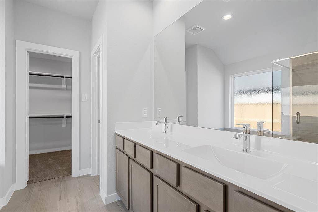 This primary bathroom is definitely move-in ready! Featuring stained cabinets with light countertops and dual vanities, spacious walk-in closet with shelving, high ceilings, custom paint, sleek and dark modern finishes.