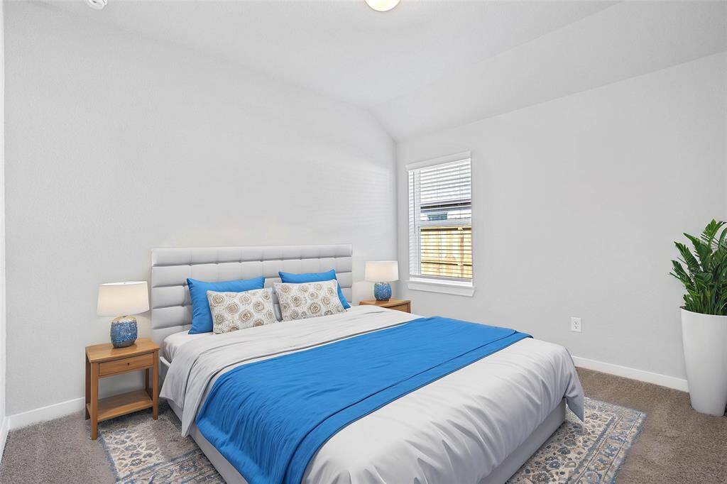 This secondary bedroom features high ceilings, lighting, custom paint, plush carpet, and a large window with privacy blinds!