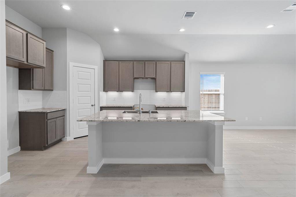 This kitchen is by far any chef’s dream! This spacious kitchen features high ceilings, stained wood cabinets with under cabinet lighting, granite countertops, large kitchen island with extended counter space for a breakfast bar, modern tile backsplash, recessed lighting, and a walk-in pantry all overlooking your huge family room.