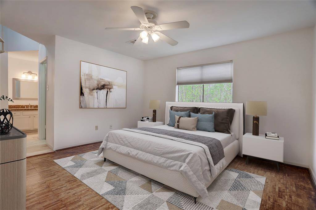 This is the primary bedroom, equipped with wooden flooring and a new, lighted ceiling fan. To the left of the frame is the master bathroom, with a combined bathtub and shower. Digitally Staged.