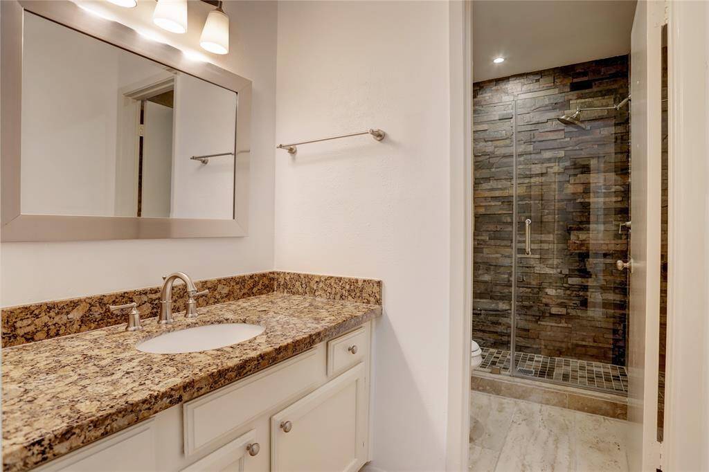 The primary bathroom features a spacious walk-in shower with modern tiling, a sink, and an abundance of countertop space. Take note of the up-to-date walk-in shower.